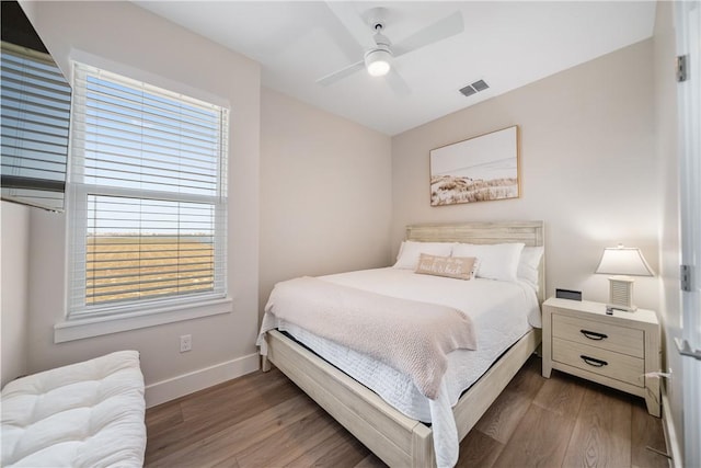 bedroom with wood finished floors, visible vents, and multiple windows