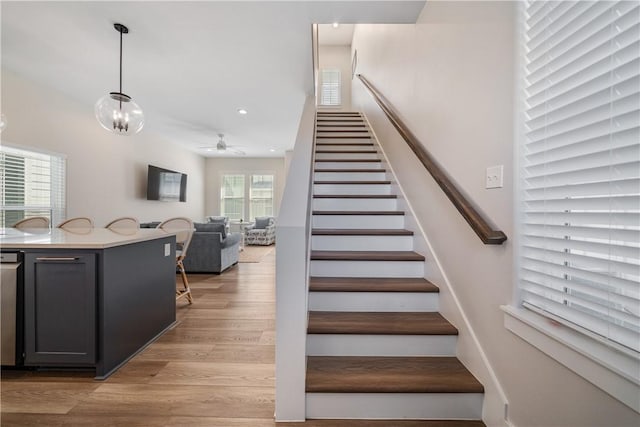 stairs with a ceiling fan, wood finished floors, and recessed lighting