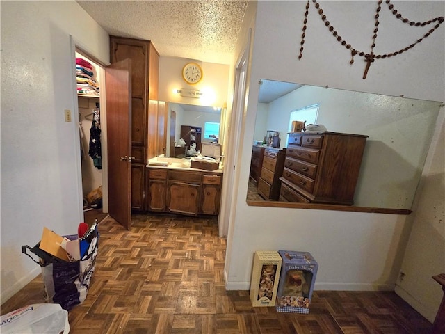 bathroom with vanity, baseboards, and a textured ceiling