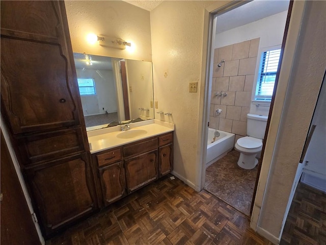 full bath featuring toilet, baseboards, bathtub / shower combination, vanity, and a textured wall