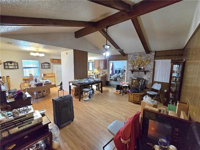 living room with ceiling fan with notable chandelier, a textured ceiling, wooden walls, lofted ceiling with beams, and light hardwood / wood-style flooring