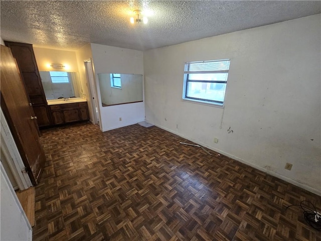 unfurnished bedroom featuring a textured ceiling, ensuite bathroom, and a sink