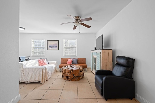 living area with light tile patterned floors, a ceiling fan, and baseboards