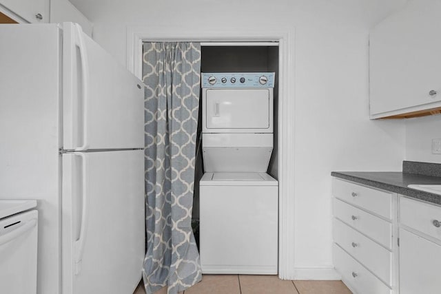 clothes washing area with light tile patterned floors, laundry area, and stacked washing maching and dryer