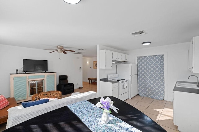 kitchen featuring white appliances, light tile patterned floors, visible vents, white cabinets, and a sink