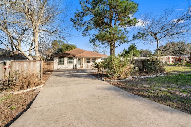 view of front of property featuring stucco siding, driveway, and fence