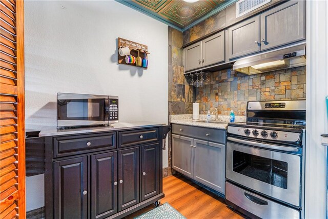 3938 Surfside Blvd Unit 2244, Corpus Christi, TX 78402 - kitchen with stainless steel appliances, tasteful backsplash, visible vents, under cabinet range hood, and light wood-style flooring