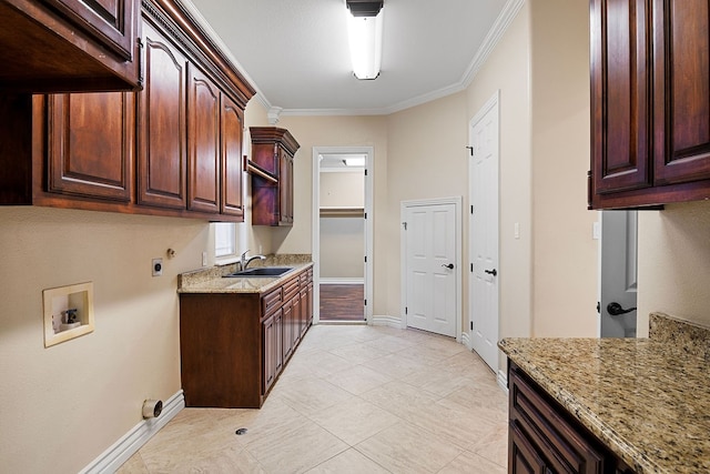 kitchen featuring light stone counters, ornamental molding, and sink