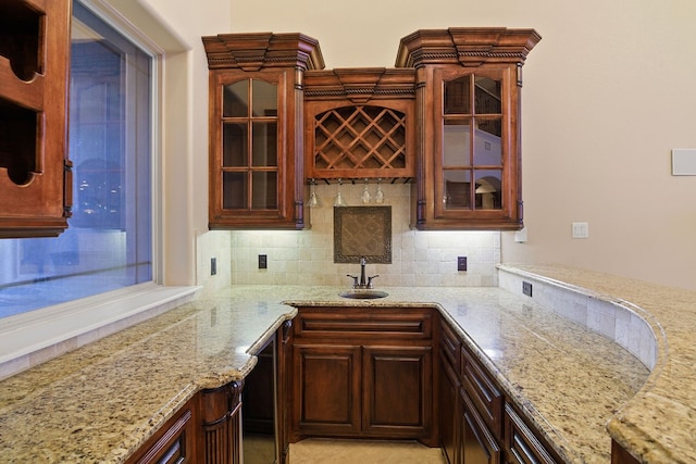 kitchen featuring tasteful backsplash, light stone countertops, and sink