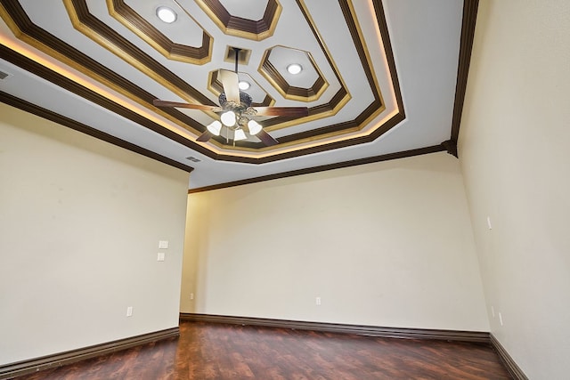 unfurnished room featuring a tray ceiling, ceiling fan, dark wood-type flooring, and ornamental molding