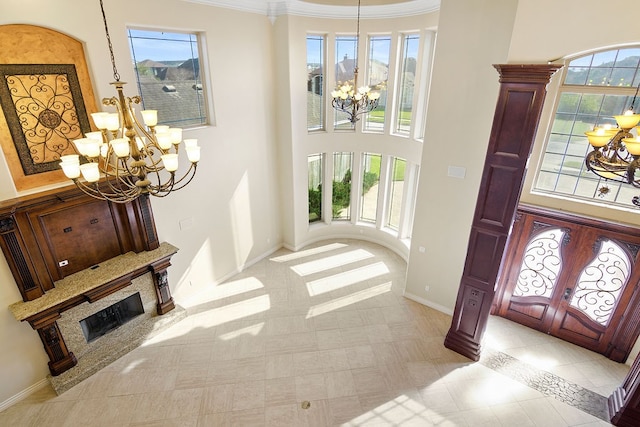 tiled entryway with a healthy amount of sunlight, a premium fireplace, crown molding, and french doors