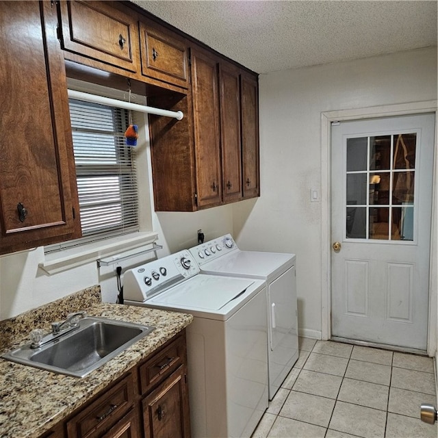 laundry area with cabinets, sink, a textured ceiling, light tile patterned floors, and washer and dryer