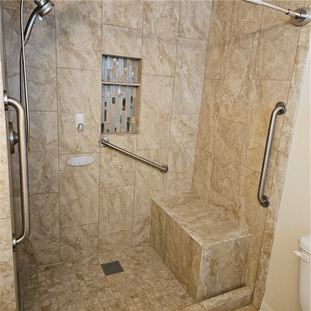 bathroom with a tile shower and toilet