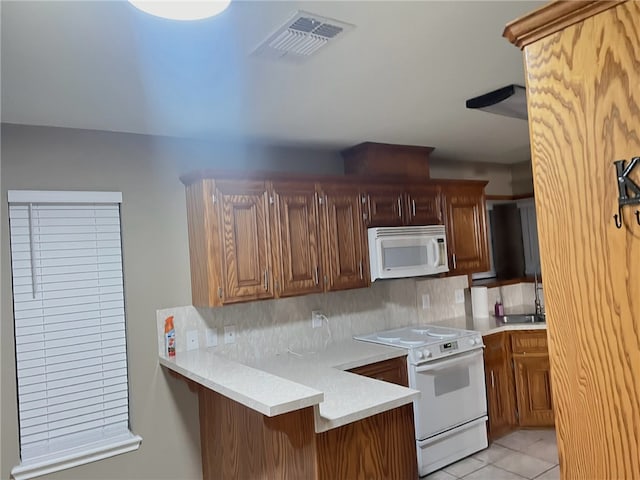 kitchen featuring white appliances, a kitchen breakfast bar, light tile patterned flooring, decorative backsplash, and kitchen peninsula