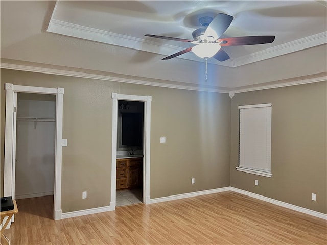 unfurnished bedroom featuring connected bathroom, ornamental molding, ceiling fan, light wood-type flooring, and a closet