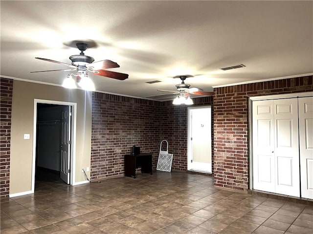 unfurnished living room with ceiling fan, ornamental molding, and brick wall