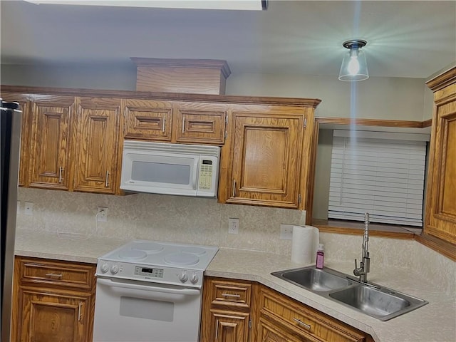 kitchen with tasteful backsplash, white appliances, decorative light fixtures, and sink