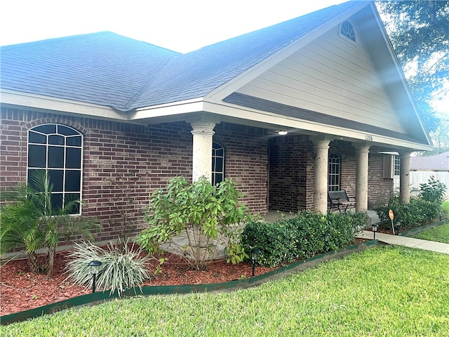 view of side of home featuring covered porch and a lawn