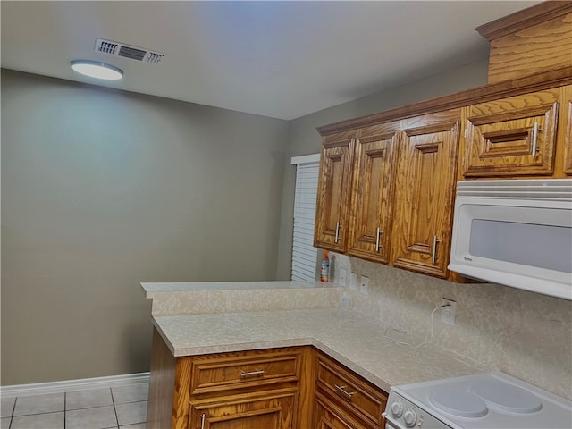 kitchen featuring light tile patterned floors, white appliances, and kitchen peninsula