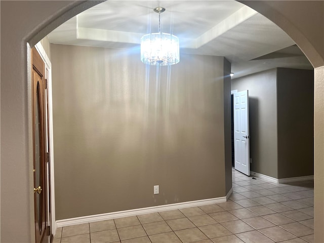 empty room with light tile patterned flooring and a tray ceiling