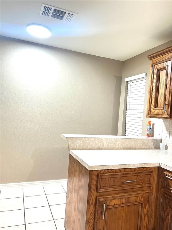 kitchen with tasteful backsplash, light tile patterned floors, and kitchen peninsula