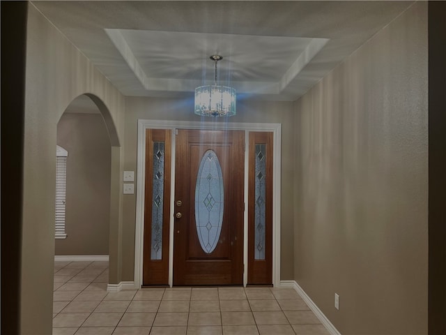 tiled entryway with a chandelier and a tray ceiling