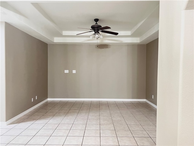 tiled spare room featuring a tray ceiling and ceiling fan