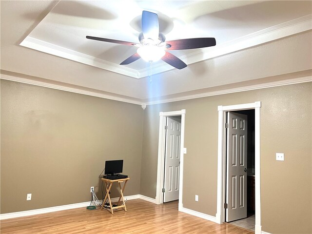 interior space featuring crown molding, a raised ceiling, ceiling fan, and light wood-type flooring