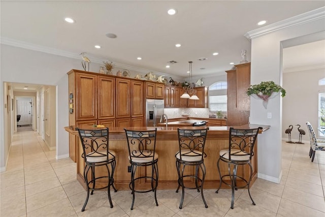 1618 Cantera Bay, Corpus Christi, TX 78418 - kitchen with stainless steel fridge with ice dispenser, brown cabinets, decorative backsplash, a breakfast bar area, and recessed lighting