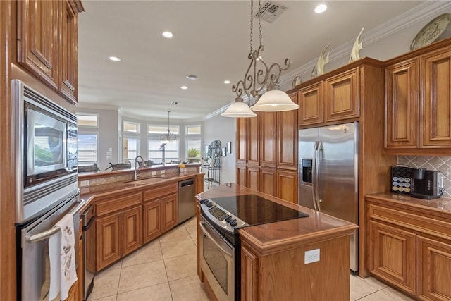 1618 Cantera Bay, Corpus Christi, TX 78418 - kitchen featuring stainless steel appliances, a sink, brown cabinetry, decorative backsplash, and light tile patterned floors