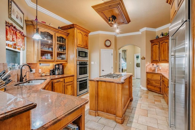 5325 Wild Olive, Corpus Christi, TX 78413 - kitchen featuring built in appliances, a sink, arched walkways, brown cabinetry, and backsplash