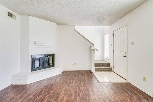 6702 Everhart Unit N102, Corpus Christi, TX 78413 - entrance foyer with stairway, a textured ceiling, wood finished floors, and a brick fireplace
