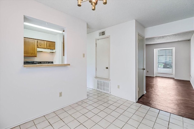 6702 Everhart Unit N102, Corpus Christi, TX 78413 - unfurnished room with a textured ceiling, a chandelier, and light tile patterned flooring
