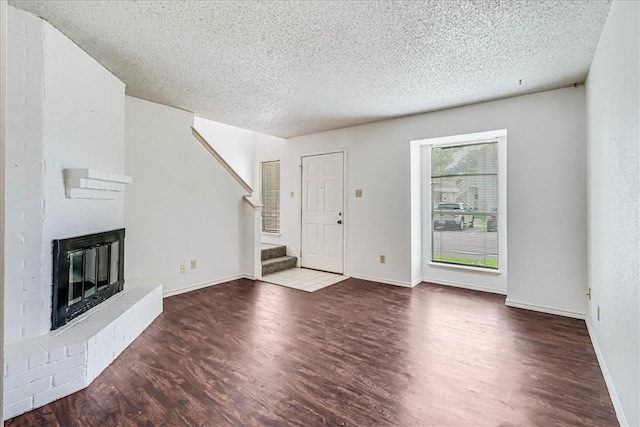 6702 Everhart Unit N102, Corpus Christi, TX 78413 - unfurnished living room with wood finished floors, a textured ceiling, a fireplace, and stairs