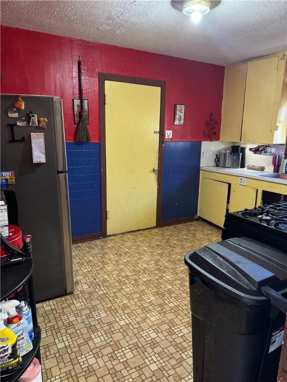 208 W Plasuela St, Refugio, TX 78377 - kitchen featuring stainless steel refrigerator and a textured ceiling