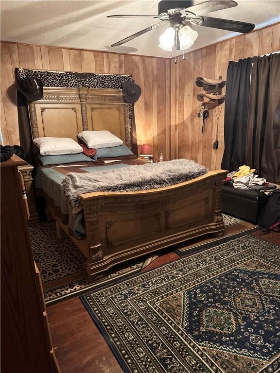 208 W Plasuela St, Refugio, TX 78377 - bedroom featuring ceiling fan, hardwood / wood-style floors, a textured ceiling, and wood walls