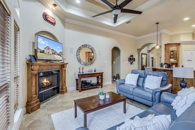 4530 Ballad Tree Dr, Corpus Christi, TX 78410 - living room featuring arched walkways, ceiling fan, ornamental molding, a warm lit fireplace, and baseboards