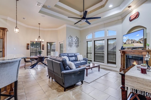 tiled living room with ornamental molding, a towering ceiling, ceiling fan with notable chandelier, and a raised ceiling