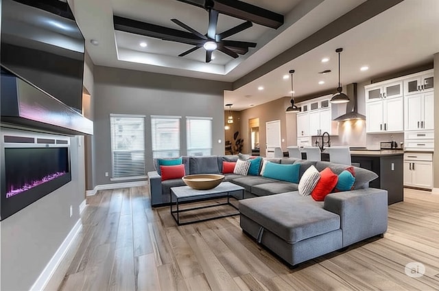 15122 Aquarius St, Corpus Christi, TX 78418 - living room with a ceiling fan, light wood-style floors, recessed lighting, a glass covered fireplace, and a raised ceiling