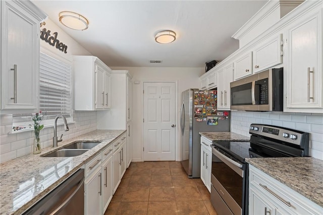 kitchen featuring appliances with stainless steel finishes, sink, white cabinets, and light stone counters