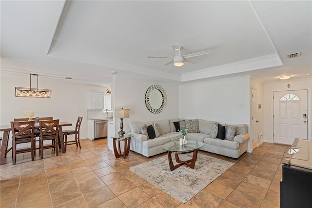 living room featuring a raised ceiling, ornamental molding, and ceiling fan