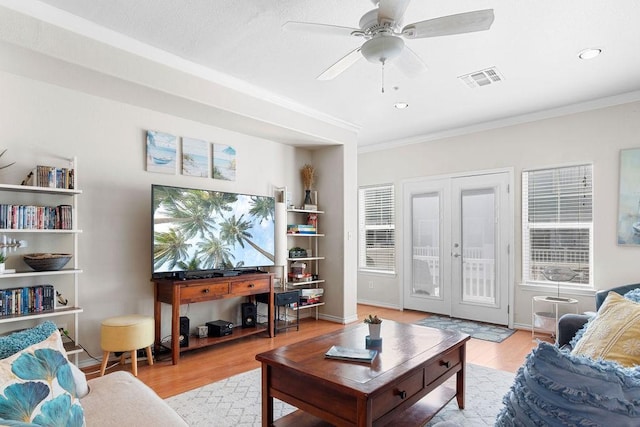 living area with visible vents, a ceiling fan, ornamental molding, french doors, and light wood-style floors