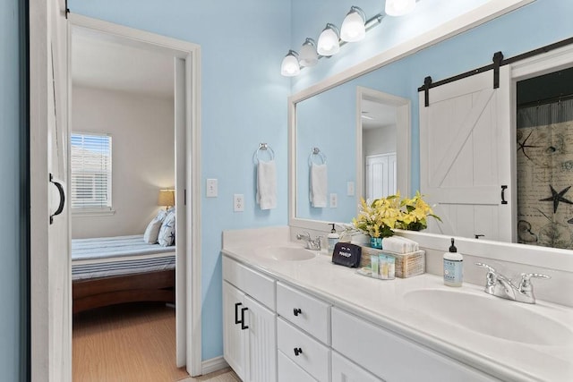 bathroom featuring wood finished floors, a sink, ensuite bathroom, and double vanity