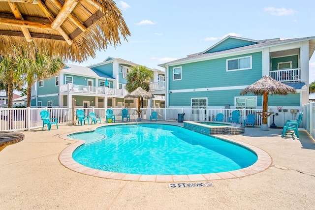 view of swimming pool featuring a patio area, a pool with connected hot tub, and fence