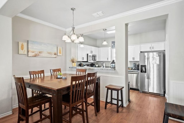 dining area with a chandelier, visible vents, crown molding, and wood finished floors