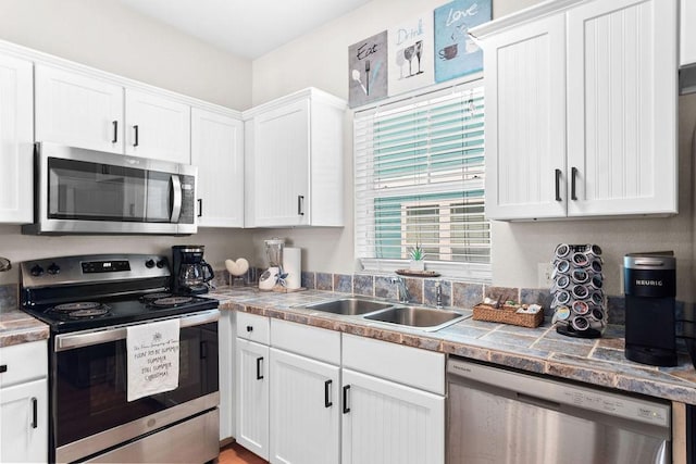 kitchen with appliances with stainless steel finishes, white cabinets, and a sink