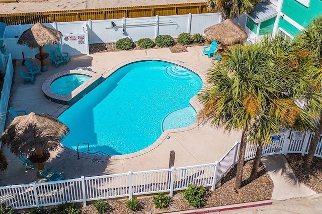 view of pool featuring a pool with connected hot tub, a fenced backyard, and a patio