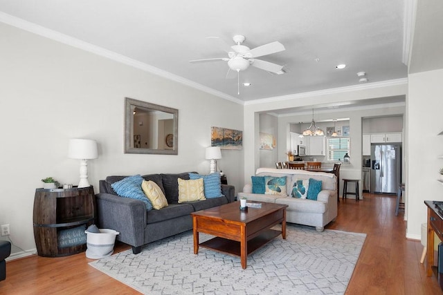 living area featuring ceiling fan, crown molding, baseboards, and wood finished floors