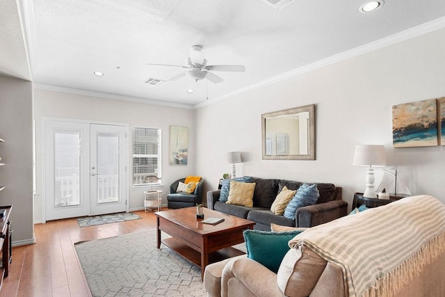 living room with visible vents, hardwood / wood-style floors, ornamental molding, a ceiling fan, and baseboards