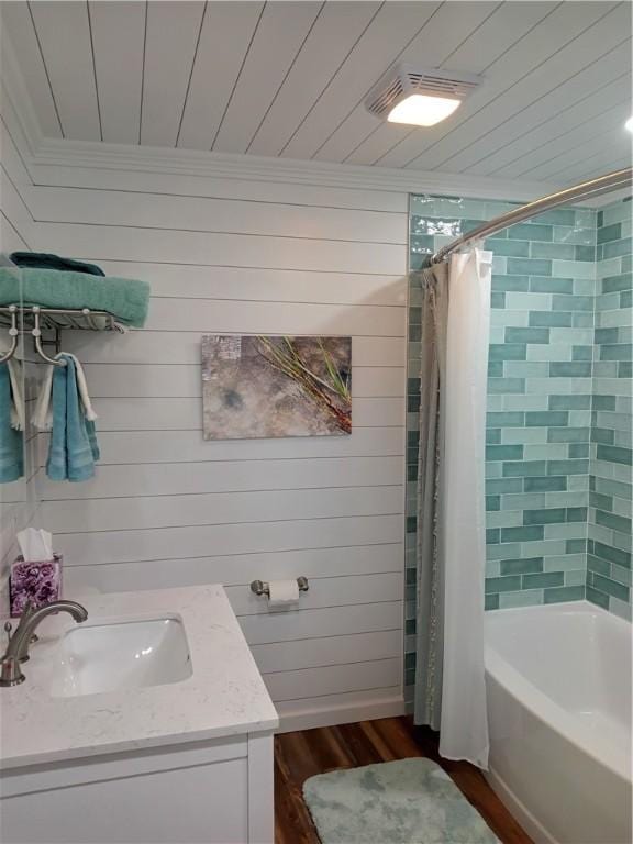 bathroom featuring wooden walls, vanity, shower / tub combo, and hardwood / wood-style flooring